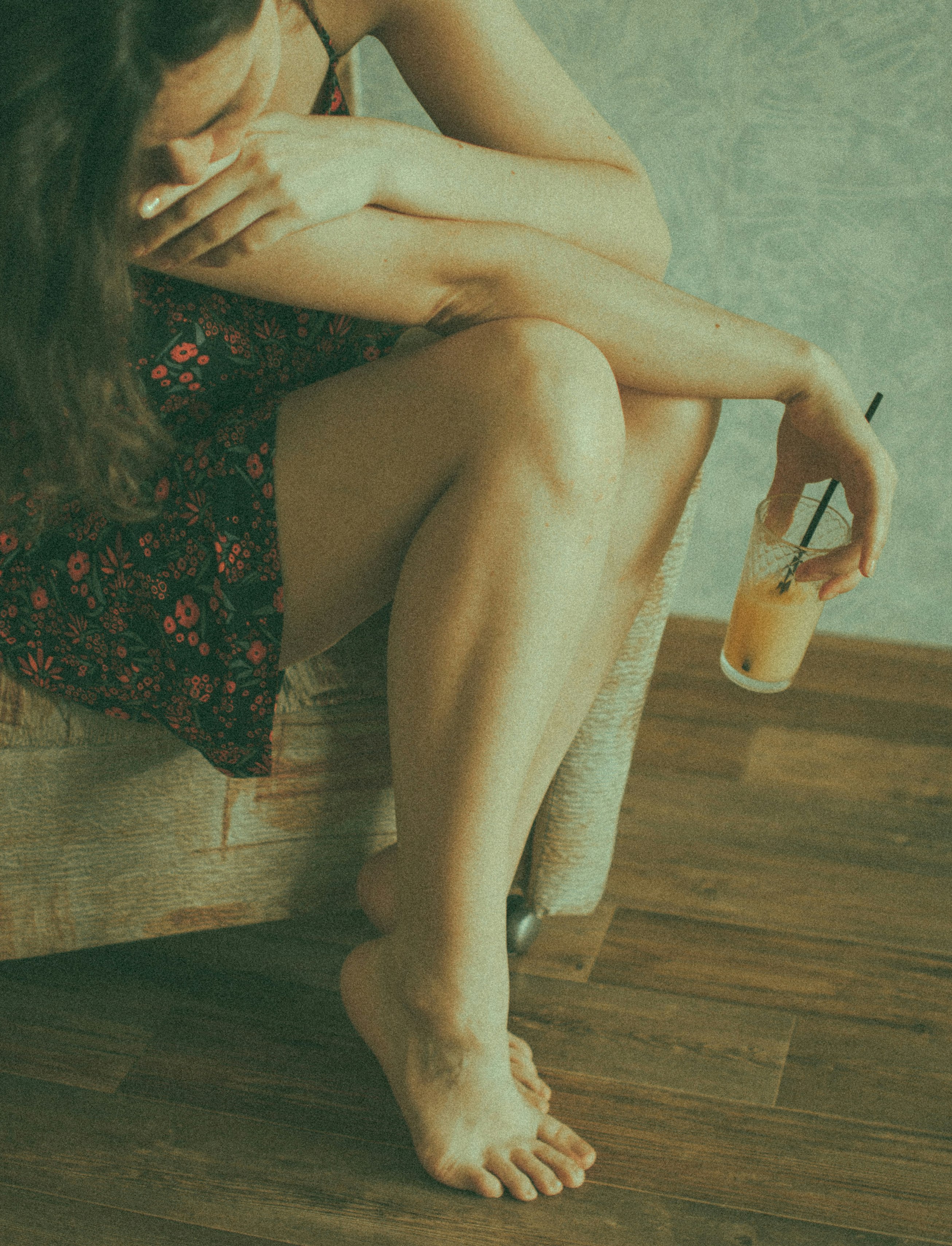 woman in black and red floral dress sitting on brown sofa